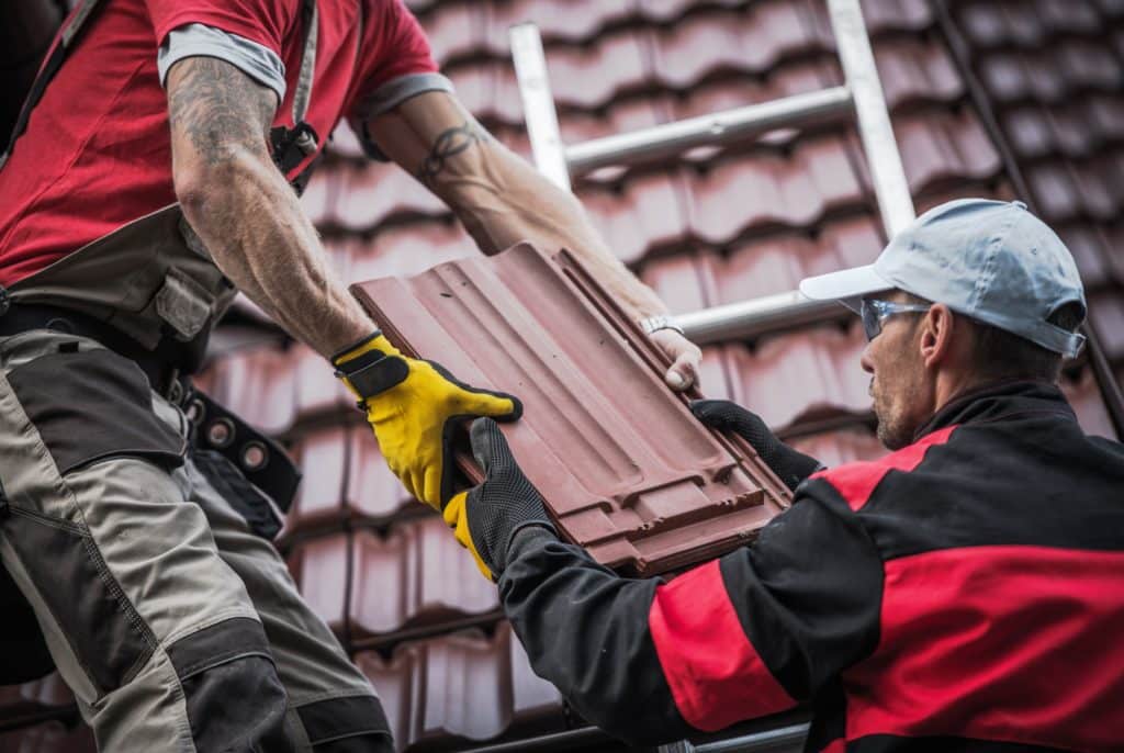 Red Roof Tiles Installation by Two Caucasian Roofers. Construction Industry Theme.