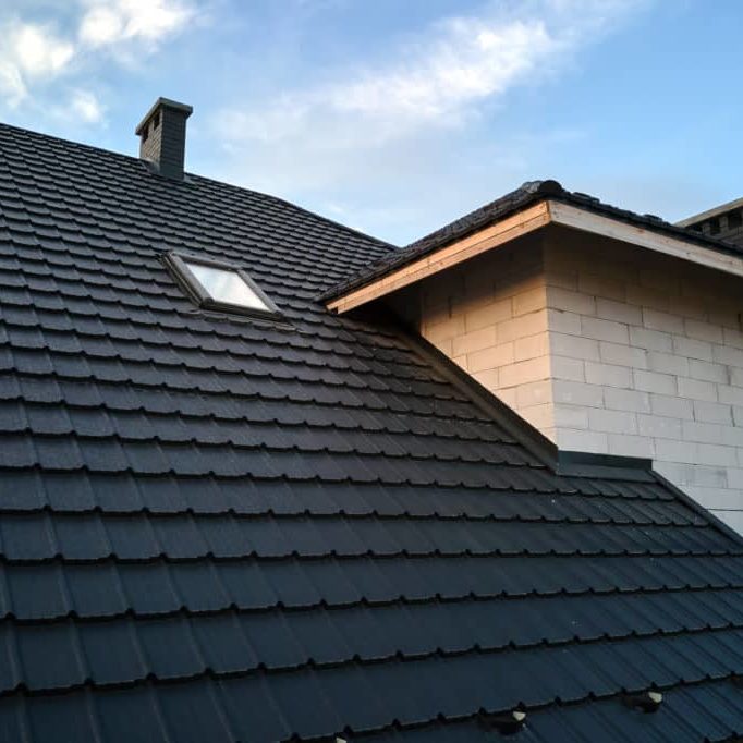 Closeup of house roof top covered with ceramic shingles. Tiled covering of building.