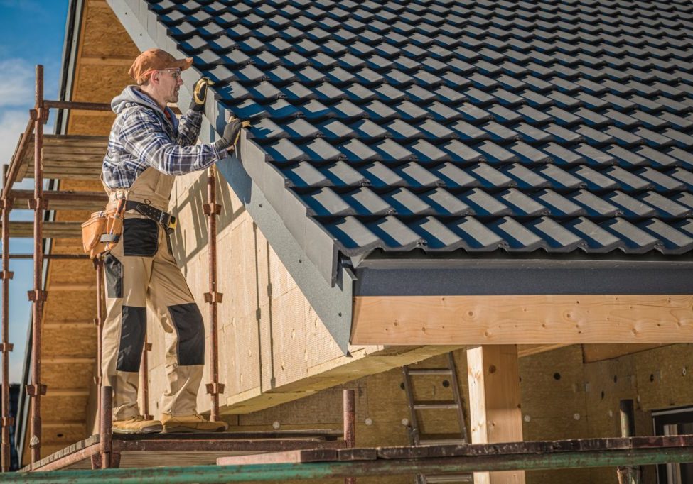 Professional Roofer Worker Finishing Ceramic Roof Tiles Installation. Smiling and Happy Worker on a Scaffolding.