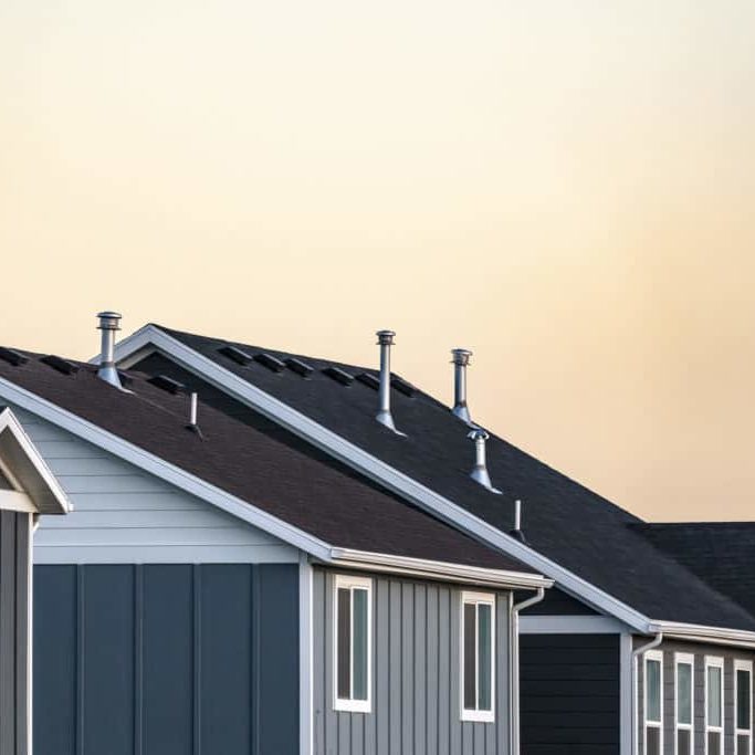 Roofs of modern urban grey timber clad houses at sunset against an orange sky