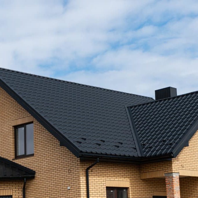 New brick house. The modern house with plastic windows and a black roof of corrugated sheet. Metal roofing.